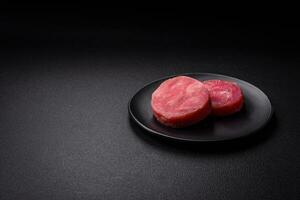 Round shape steaks of raw juicy tuna with salt and spices photo