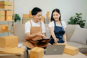 Small business entrepreneur SME freelance Asian man and woman working at home office, BOX, tablet and laptop online, marketing, packaging, delivery. photo