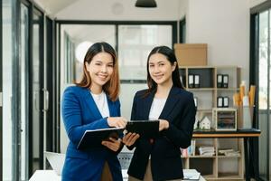 Businesswoman leading team meeting and using tablet and laptop computer with financial in office photo