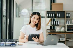 Asian businesswoman working with working notepad, tablet and laptop documents photo