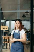 joven hembra colgando un Bienvenido firmar en frente de un café tienda. hermosa camarera o anfitriona participación un tableta preparando en un restaurante. foto