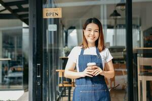 Young female hanging a welcome sign in front of a coffee shop. Beautiful waitress or hostess holding a tablet preparing  in a restaurant. photo
