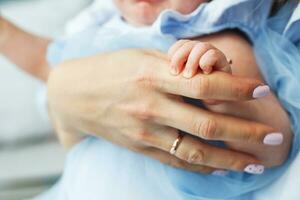 Mother holds the baby in her arms and holds her hand photo