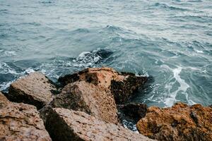 Mediterranean winter stormy seaside. Close up water with stones on the beach concept photo