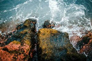 Close up water with stones on the beach concept photo. Mediterranean winter stormy seaside. Underwater rock with algae. photo