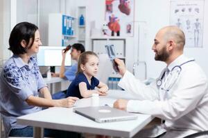 Pediatrician examining sick child xray during medical consultation in hospital office. Healthcare physician specialist in medicine providing health care services treatment examination. photo