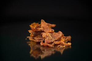 handful of dried meat marinated with spices, isolated on a black background. photo