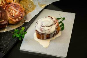 cooked baked sweet Cinnabon with cream in baking paper . photo