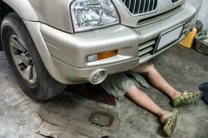 Mechanic lying down repair car in garage photo