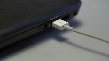 Hand inserting white USB cable into laptop isolated on white background. Media. Close up of connecting device to a computer with a cable. photo