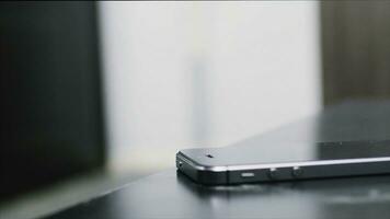 Close up of Young man hand puts mobile phone on wooden desk. Putting down cell phone on wooden table. Human hand places on table cellphone with completely discharged battery, close up view photo