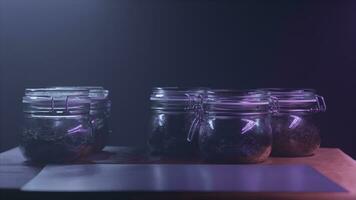 Five glass jars with different types of leaf tea standing on the table in dark room on black wall background. Action. Glass tanks with tea or spices under the dim light. photo