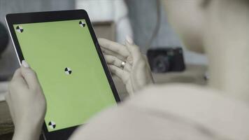 Side view of a woman holding tablet pc with green screen on wooden table background. Stock footage. Close up of a girl using Ipad with chroma key. photo