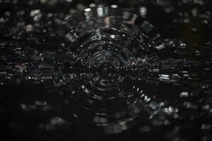 Abstract black background with silver bokeh spots and radial wave patterns. photo