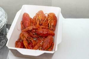 Boiled crayfish close-up in a white paper package. photo