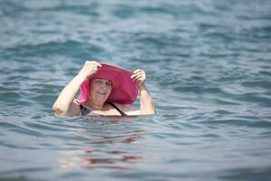 un hermosa mayor mujer se baña en el mar. foto