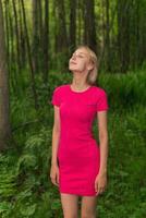 beautiful girl rejoices in the summer rain while walking in the forest photo