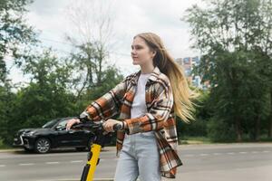 young woman on an electric scooter rides down the street photo