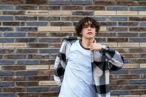 young man posing against a brick wall photo