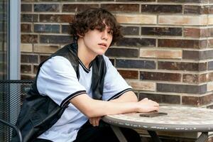 young man sitting at an outdoor cafeteria table photo