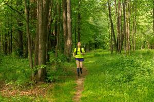 young woman jogging on a path in a natural forest park photo