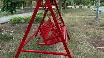 een rood Speel schommel is gelegen in speelgoed. schommel Speel zonder mensen.de tuin. stil schommel video