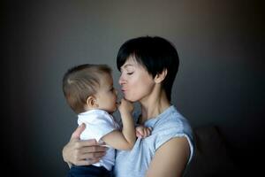 little boy plays with young beautiful mom in the bedroom photo