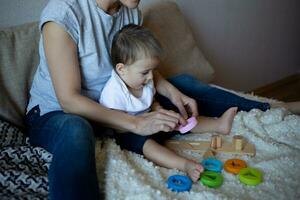 little boy plays with young beautiful mom in the bedroom photo