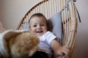 little cute boy showing tongue while sitting in a chair in the bedroom photo
