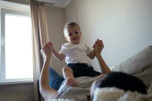 little boy plays with young beautiful mom in the bedroom photo