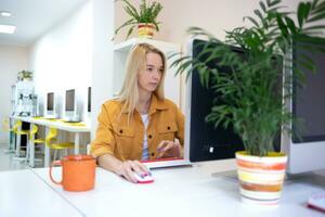 young woman sits at a computer in the office. remote work concept photo