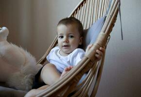 pequeño linda chico sonriente mientras sentado en un silla en el dormitorio foto