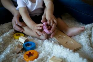 pequeño chico obras de teatro con joven hermosa mamá en el dormitorio foto