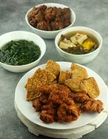 tempe and crispy chicken and tamarind vegetables and spinach, on a wooden table, selective focus photo