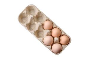 Fresh raw chicken eggs in beige color in a cardboard tray photo