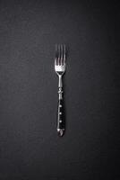 Kitchen fork made of steel on a dark textured background photo