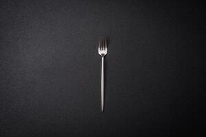 Kitchen fork made of steel on a dark textured background photo