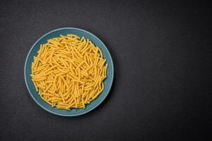 Raw whole grain wheat pasta with salt and spices in a ceramic plate photo