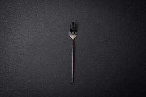 Kitchen fork made of steel on a dark textured background photo