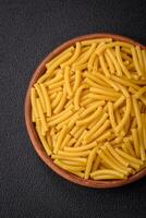 Raw whole grain wheat pasta with salt and spices in a ceramic plate photo