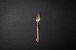 Kitchen fork made of steel on a dark textured background photo