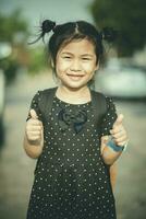 cara de asiático niños sonriente cara y firmar bueno sensación por dedo foto