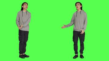 Male person creating advertisement and showing something to left or right sides on camera, pointing at thing over full body greenscreen. Young adult advertising slogan for marketing commercial. video