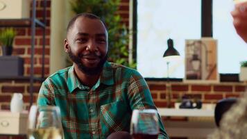 Close up shot of cheerful african american man having interesting conversation with BIPOC apartment party guests. Lively host talking with inclusive group of friends in living room video