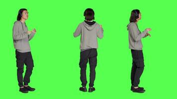 Joyful man does groovy dance moves in studio, feeling funky while he is listening to cool music. Asian male model smiling and enjoying songs on wireless headset, dancing on greenscreen. video