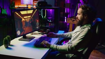 Man in dark living room playing science fiction videogame on gaming PC, concentrating on shooting foes. Gamer battling flying robots with futuristic gun in online singleplayer shooter video