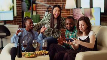 bipoc vänner tar grupp bilder med selfie kamera smartphone på lägenhet fest. glad mates i modern Hem Framställ för Foto med vin och champagne glasögon, framställning gester video