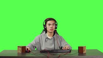 POV of person plays pc videogames at workstation, sitting on office chair over greenscreen. Modern guy having fun online with colleagues in rpg competition, wearing headset at his desk. video