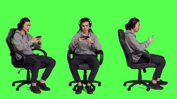 Over full body greenscreen, asian adult enjoys mobile videogames holding smartphone and participating in online action contest. Gamer uses phone to participate in new roleplaying battle. video