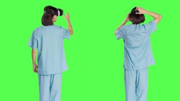 Medical personnel uses virtual reality eyewear against greenscreen set while using new interactive 3D headpiece. Clinical healthcare specialist using artificial intelligence vision. video